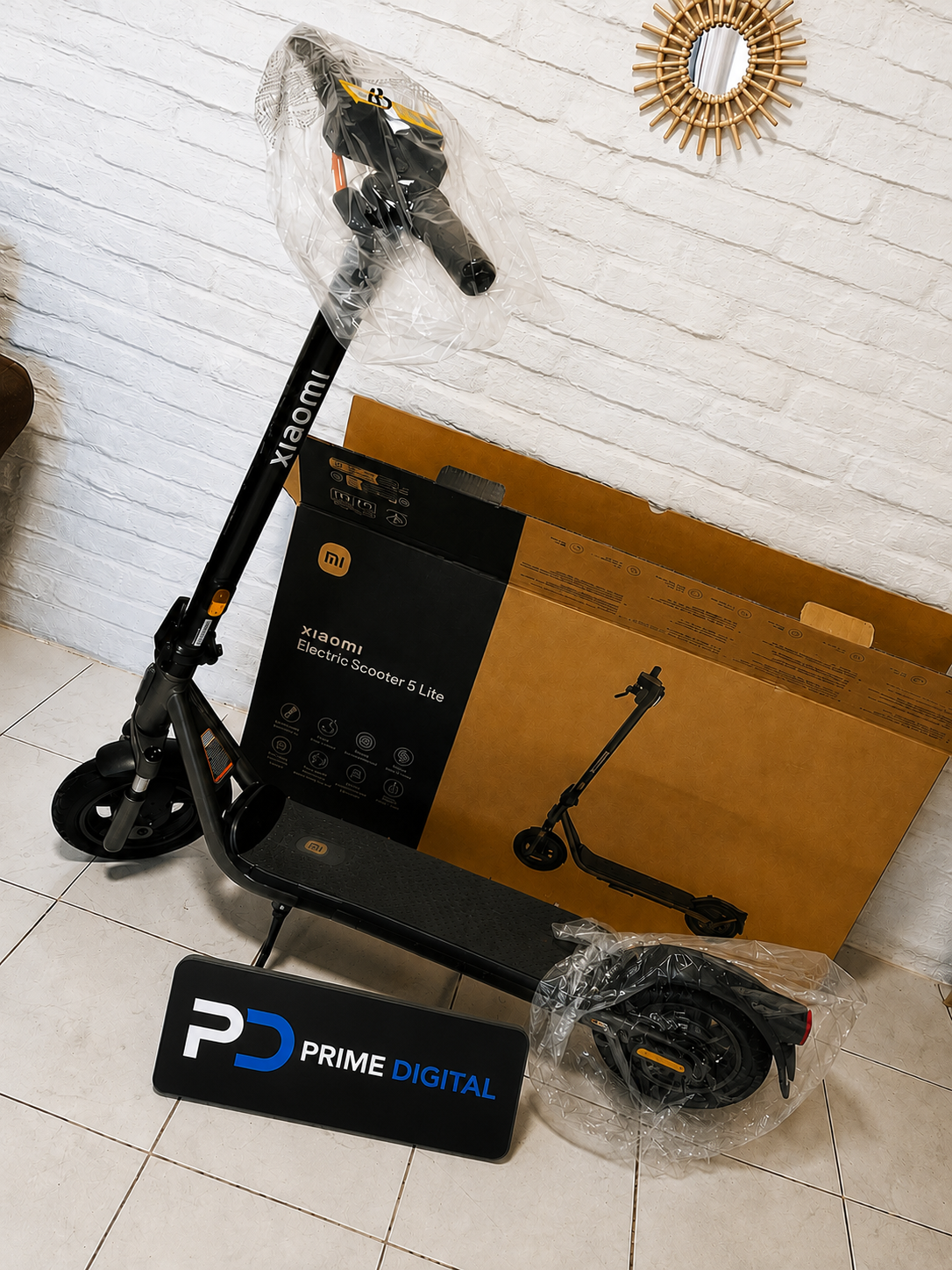 Xiaomi Electric Scooter 5 Lite junto a su caja y la placa de Prime Digital
