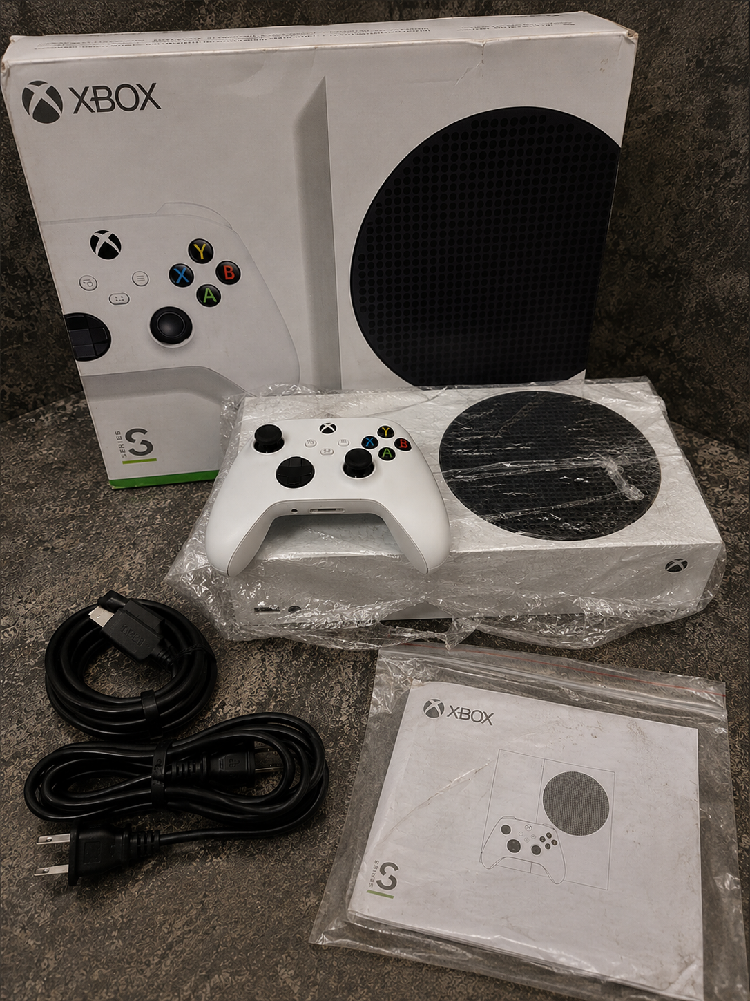 Xbox Series S blanca con control, cables y manuales preparados para la entrega
